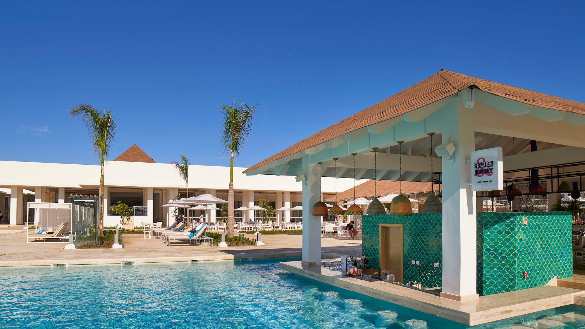 Luxury resort pool with swim-up bar, green tiles, and palm trees.