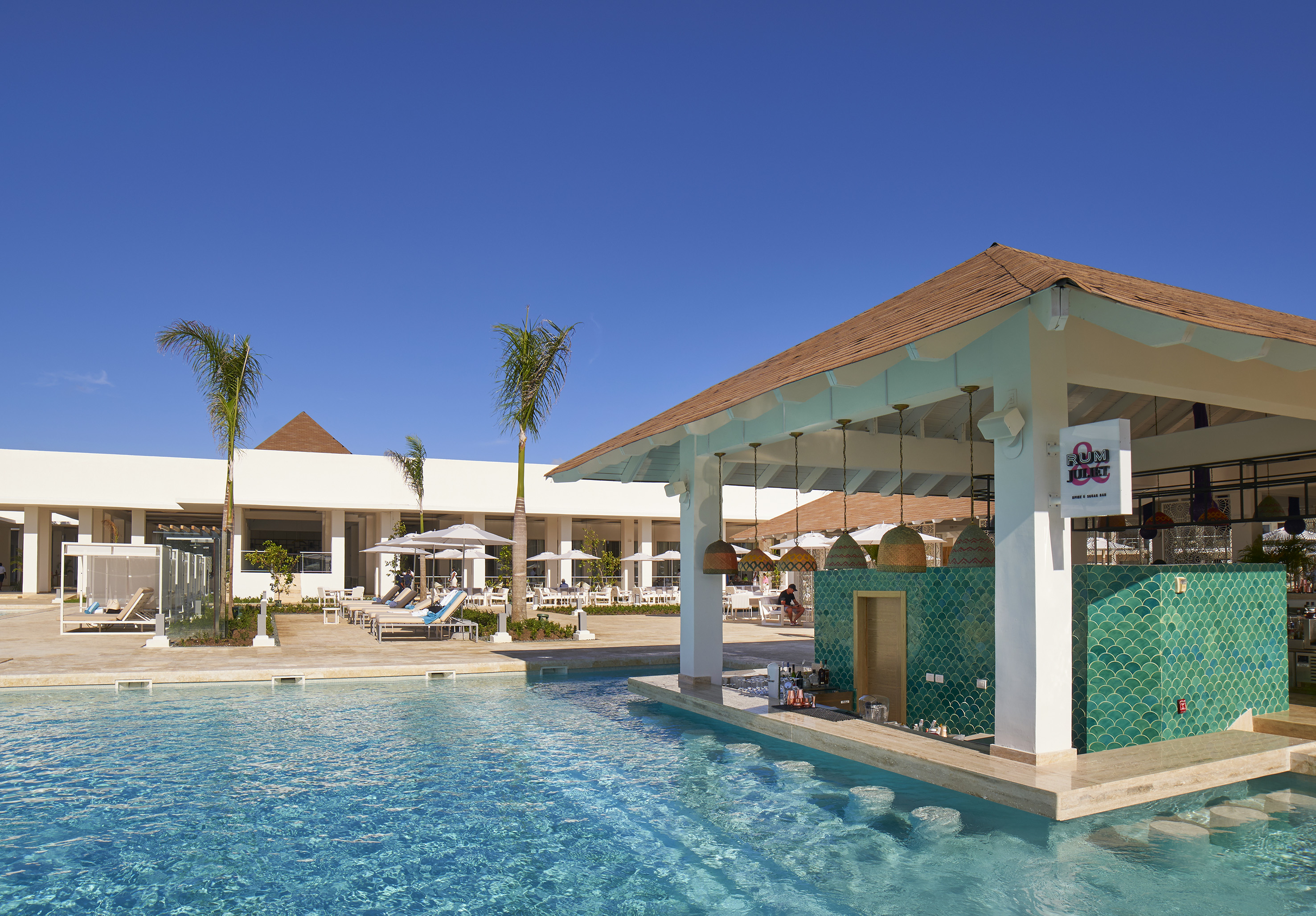 Luxury resort pool with swim-up bar, green tiles, and palm trees.