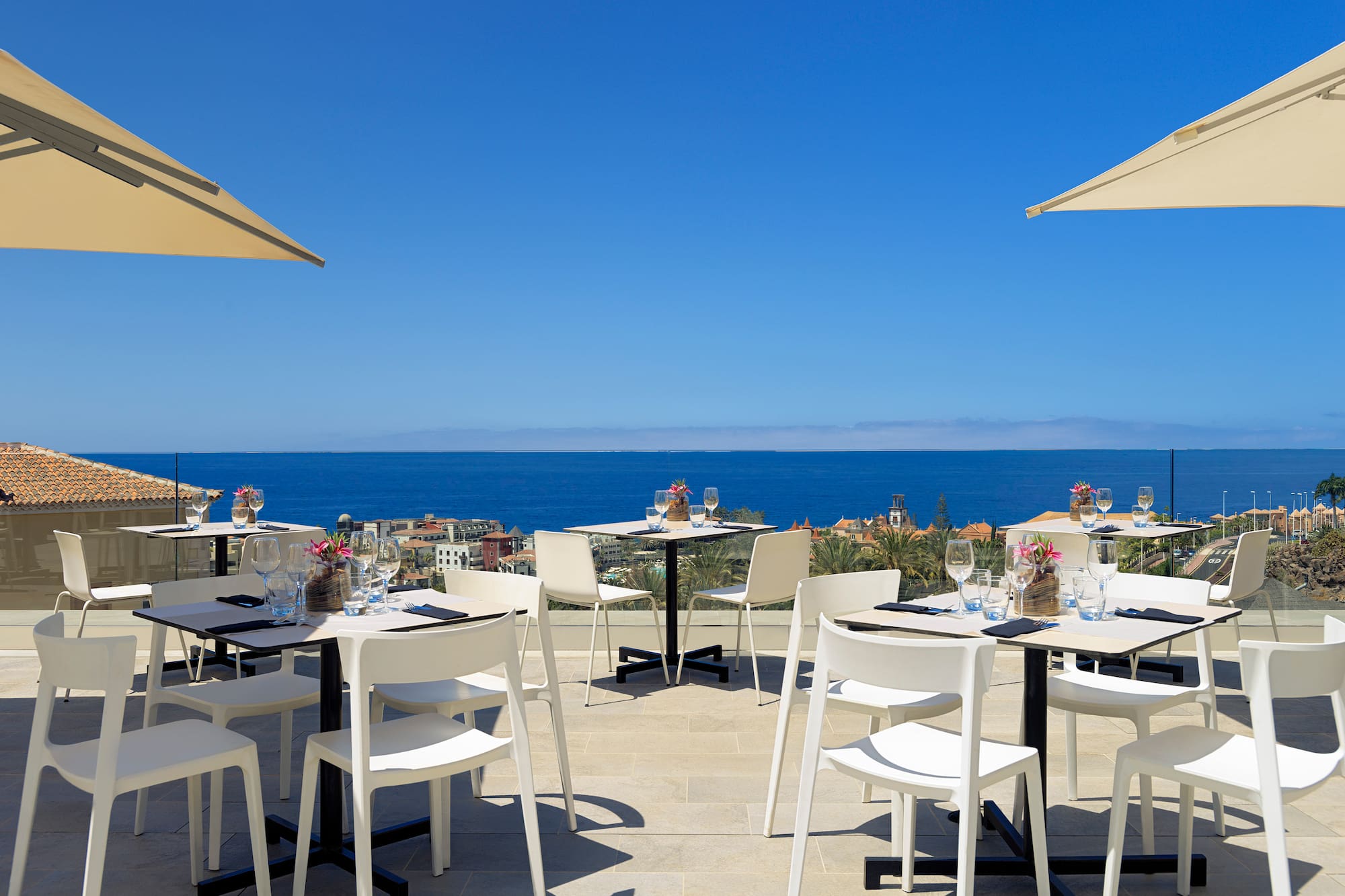 a table and chairs on a patio with a body of water in the background