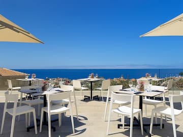 a table and chairs on a patio with a body of water in the background