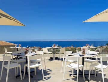 a table and chairs on a patio with a body of water in the background