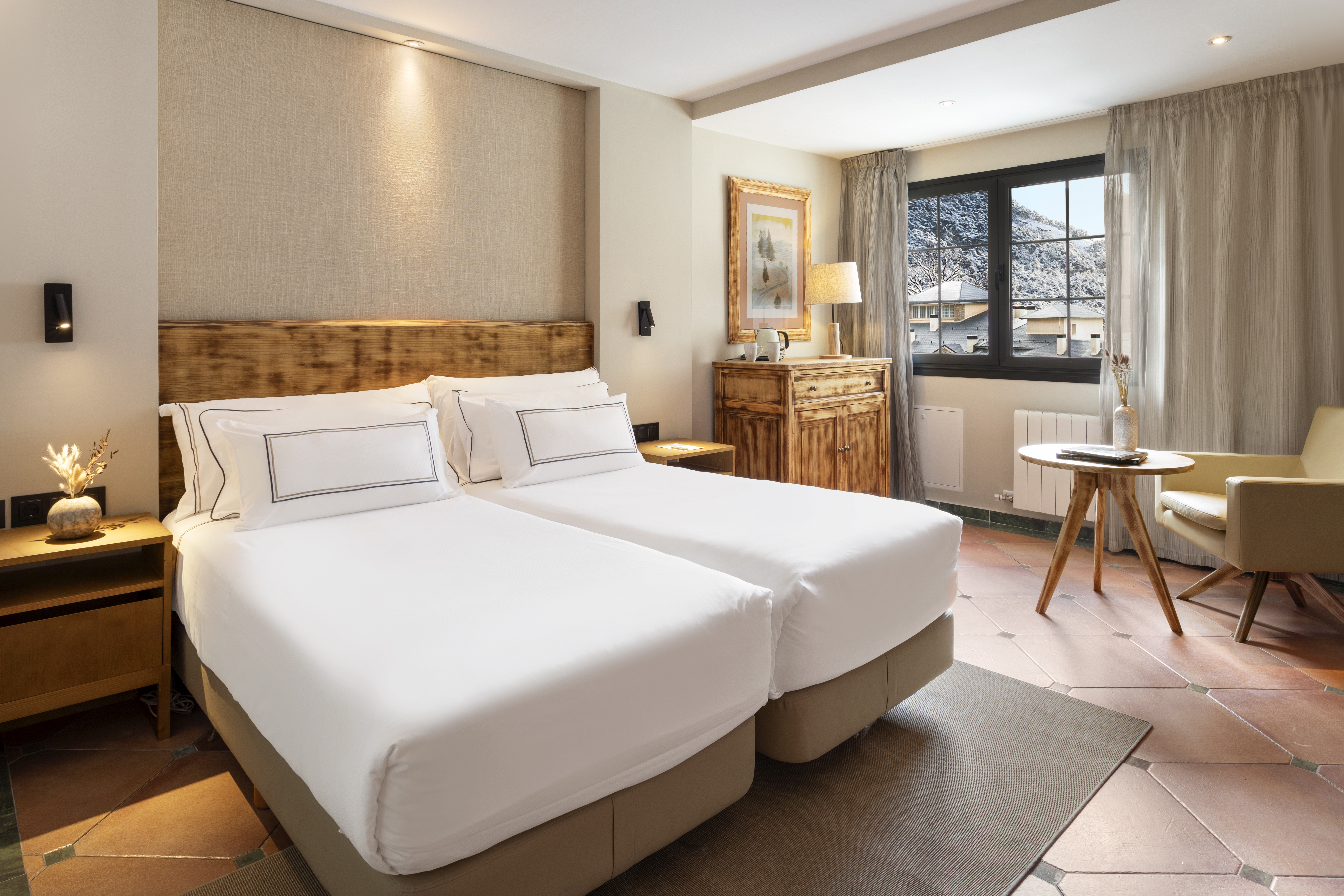 Rustic hotel room with twin beds and snowy mountain view.