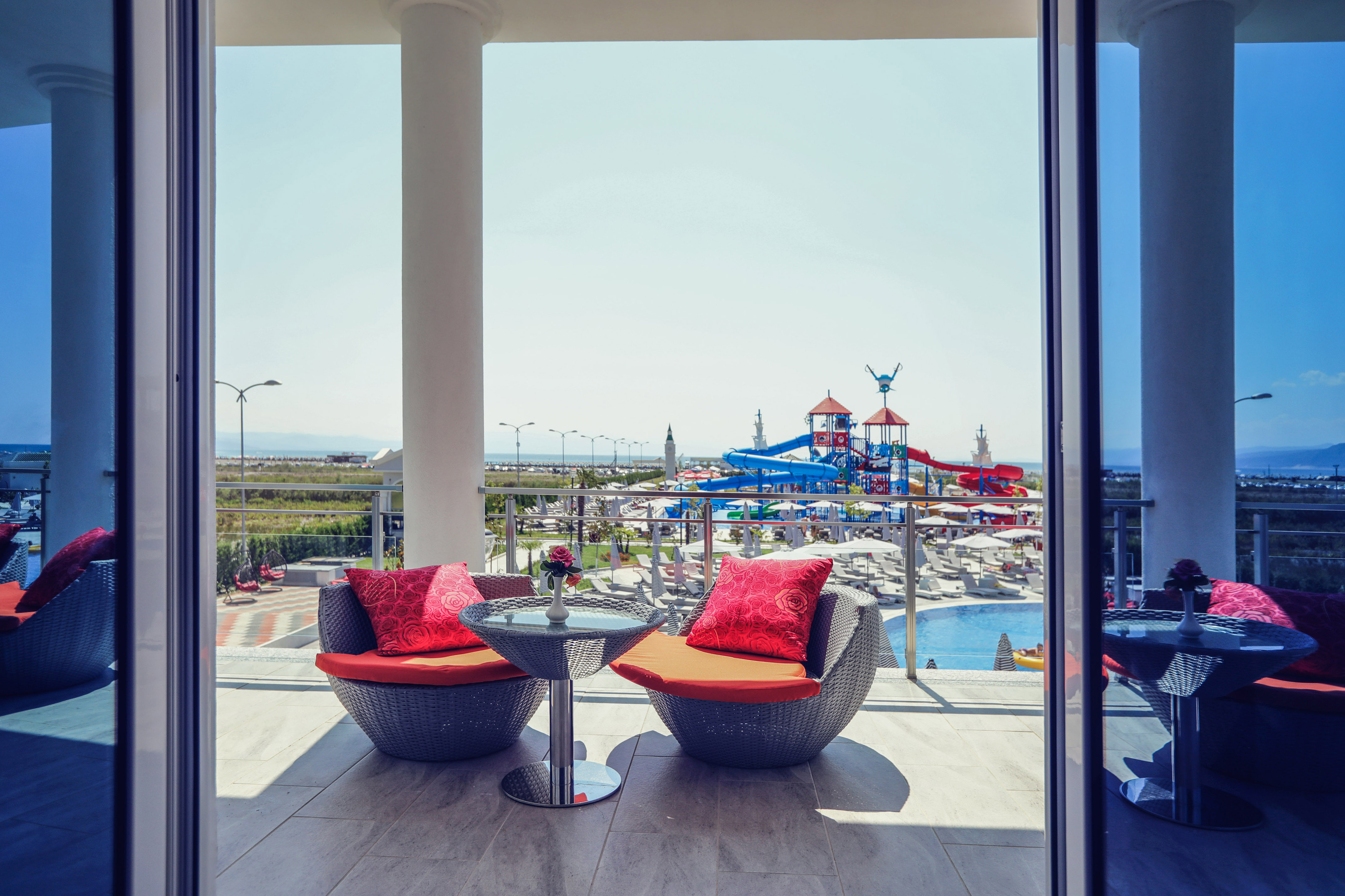 Resort balcony with chairs, aqua park, swimming pool, and sea view.