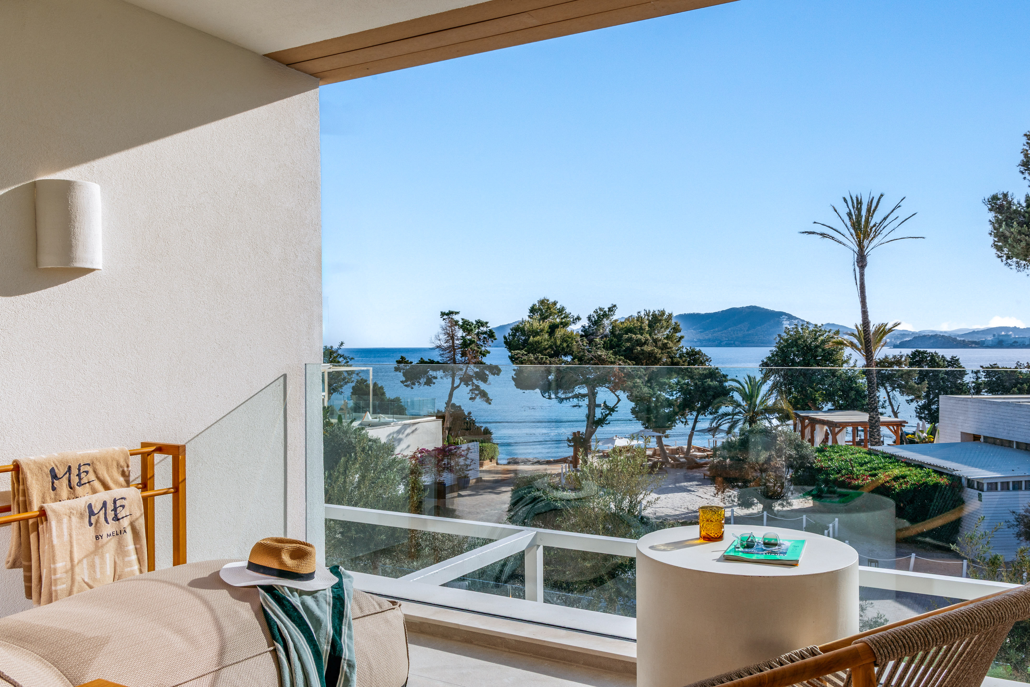 Luxury resort balcony with panoramic sea view, beach, and palm trees.