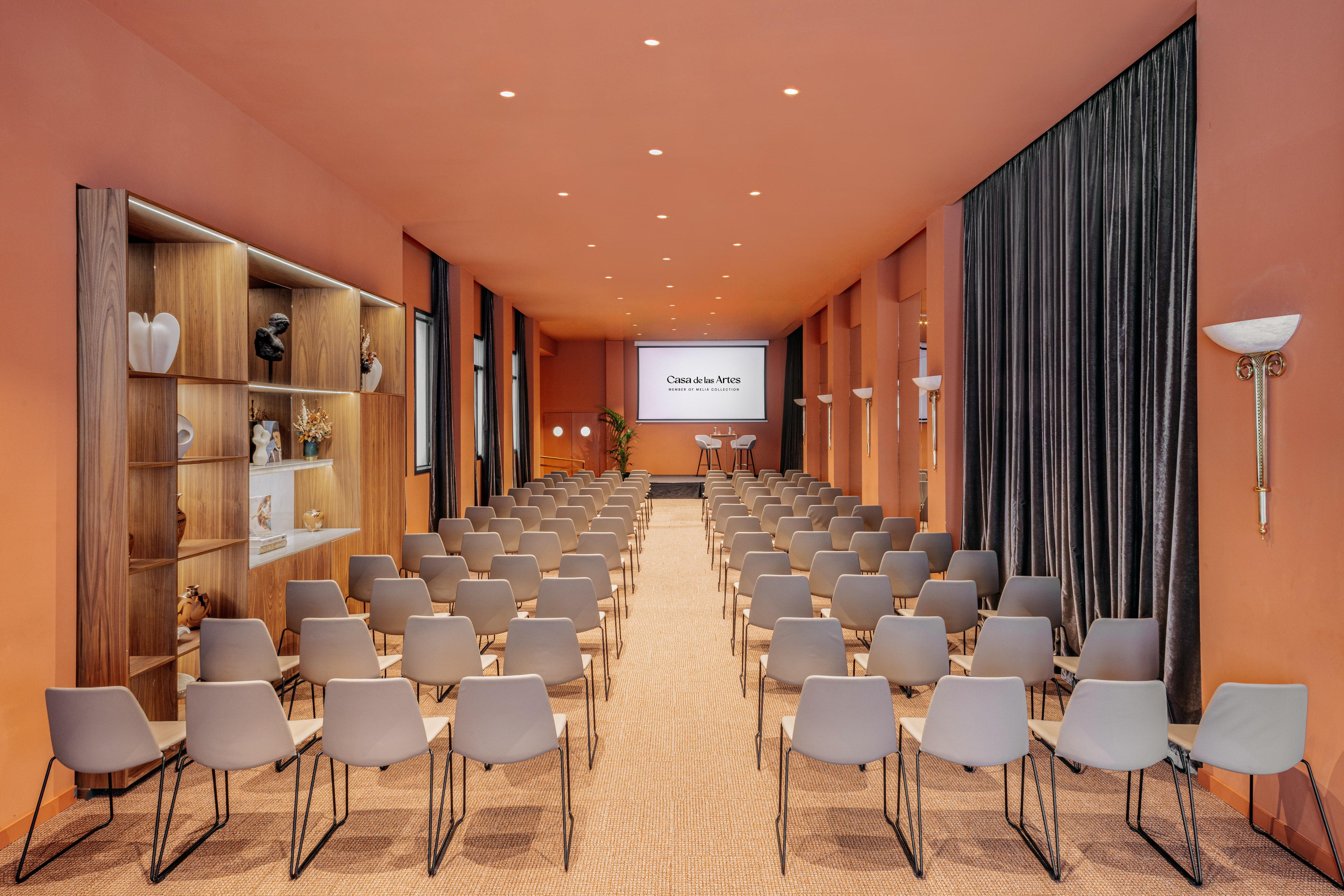 Casa de las Artes conference room with orange walls and presentation screen.