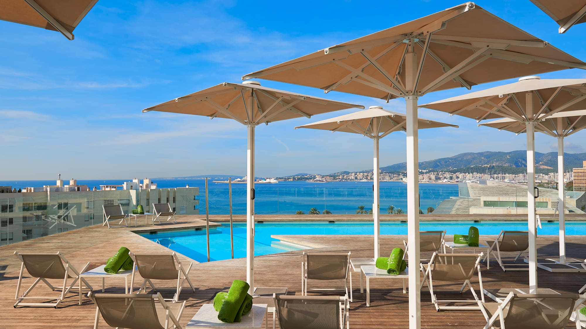 a pool with chairs and umbrellas by a building