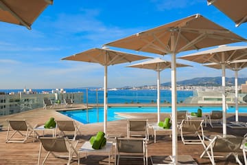 a pool with chairs and umbrellas by a building