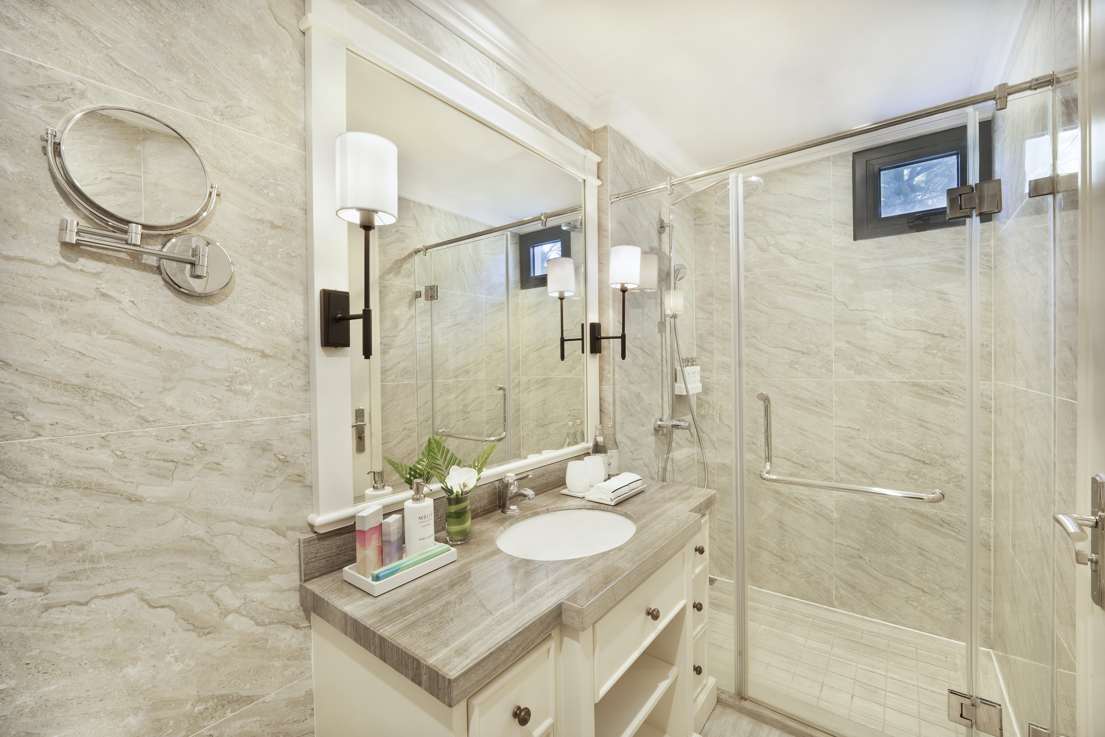 Contemporary bathroom with stone vanity, large mirror, and glass shower.