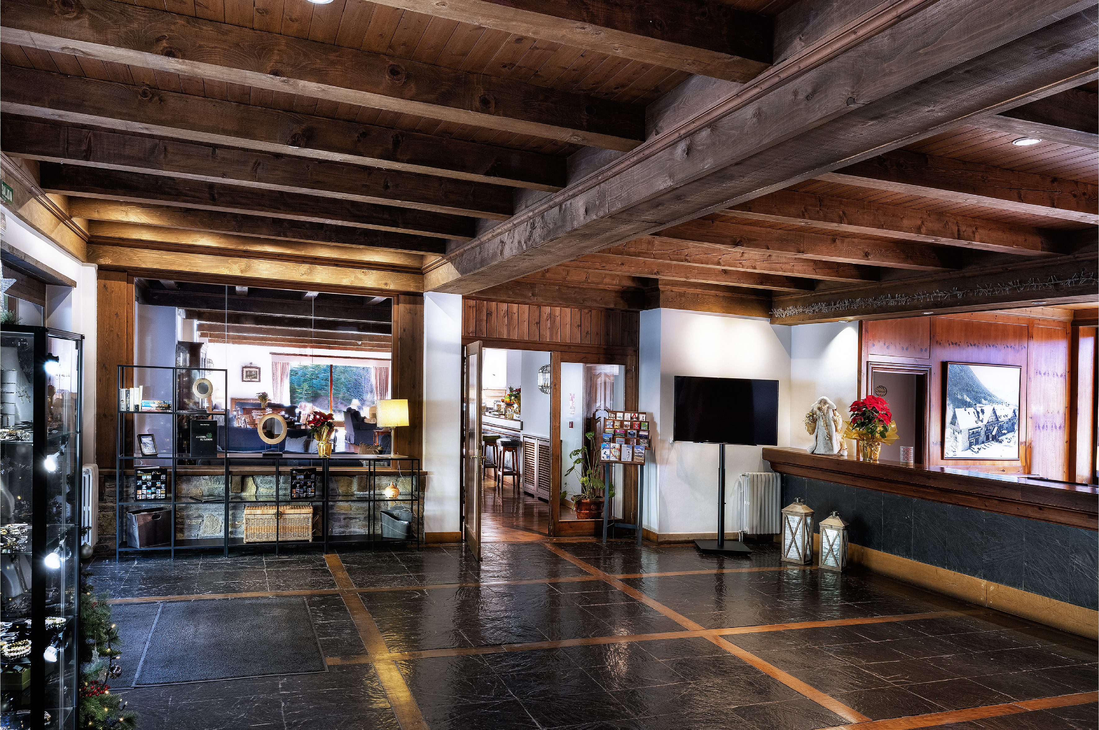Rustic hotel lobby with wooden beamed ceiling, dark tiled floor, and reception desk.