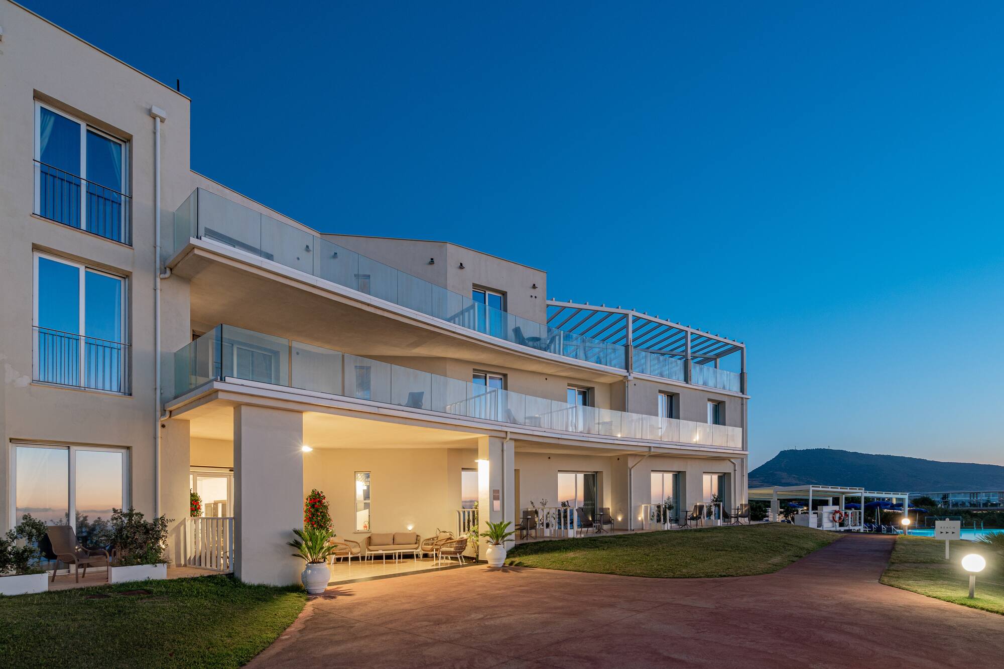 Modern resort building at twilight with glass balconies and mountain.