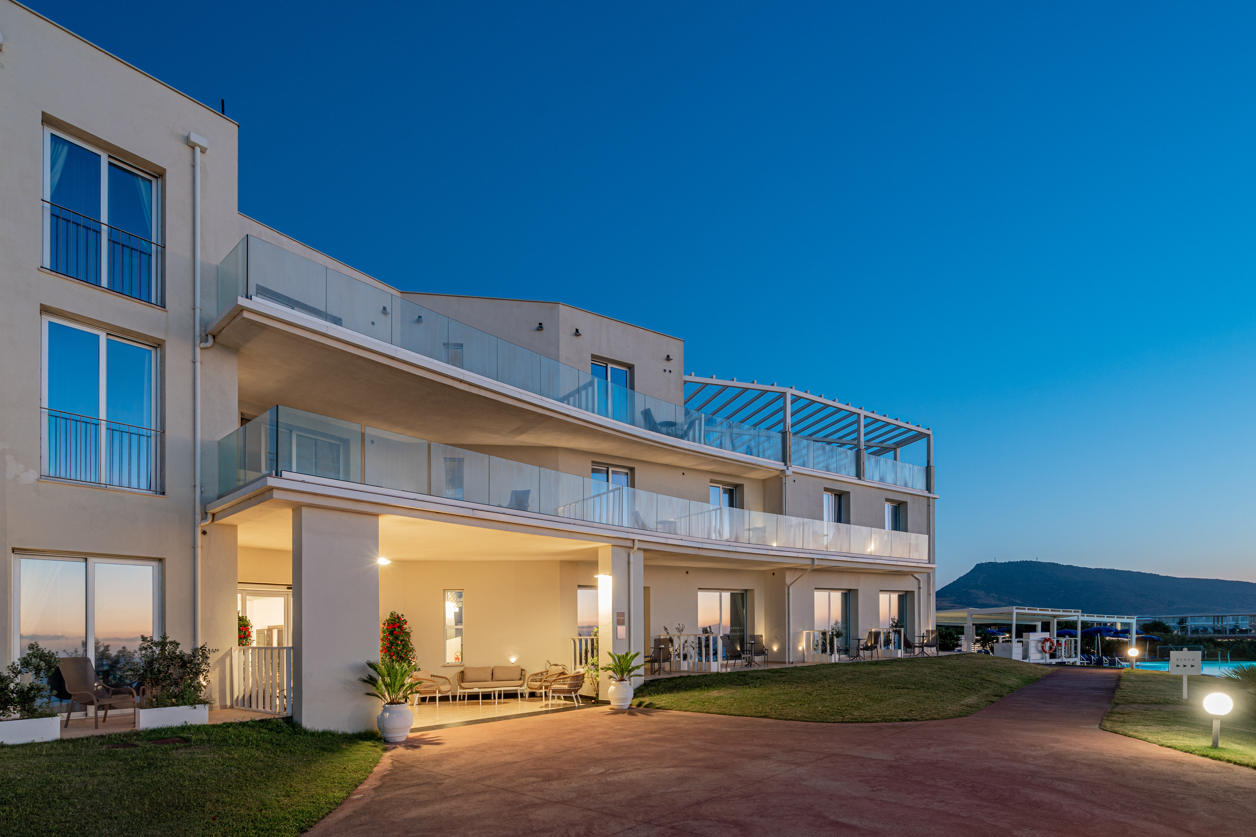 Modern resort building at twilight with glass balconies and mountain.
