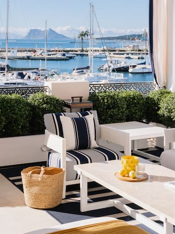 a patio with a view of boats and a mountain in the background