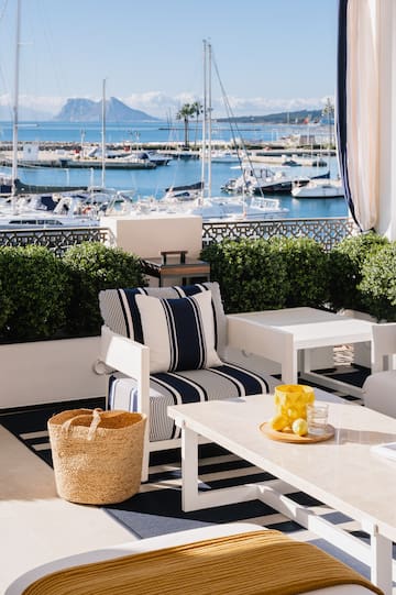 a patio with a view of boats and a mountain in the background