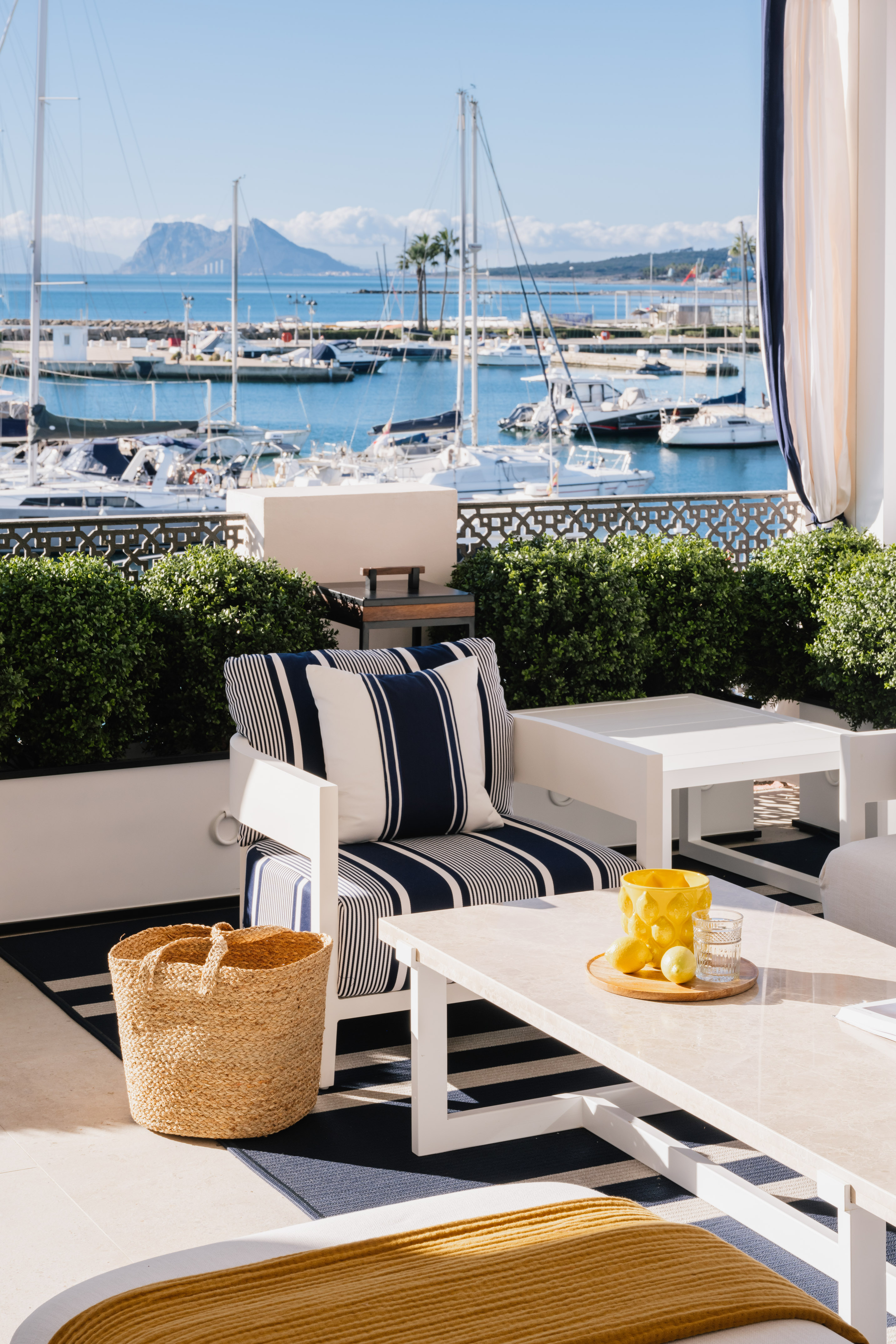 Sunny patio with striped outdoor seating, white table, and marina view.