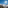 Sunny ski slopes and resort town in snowy mountains, clear blue sky.