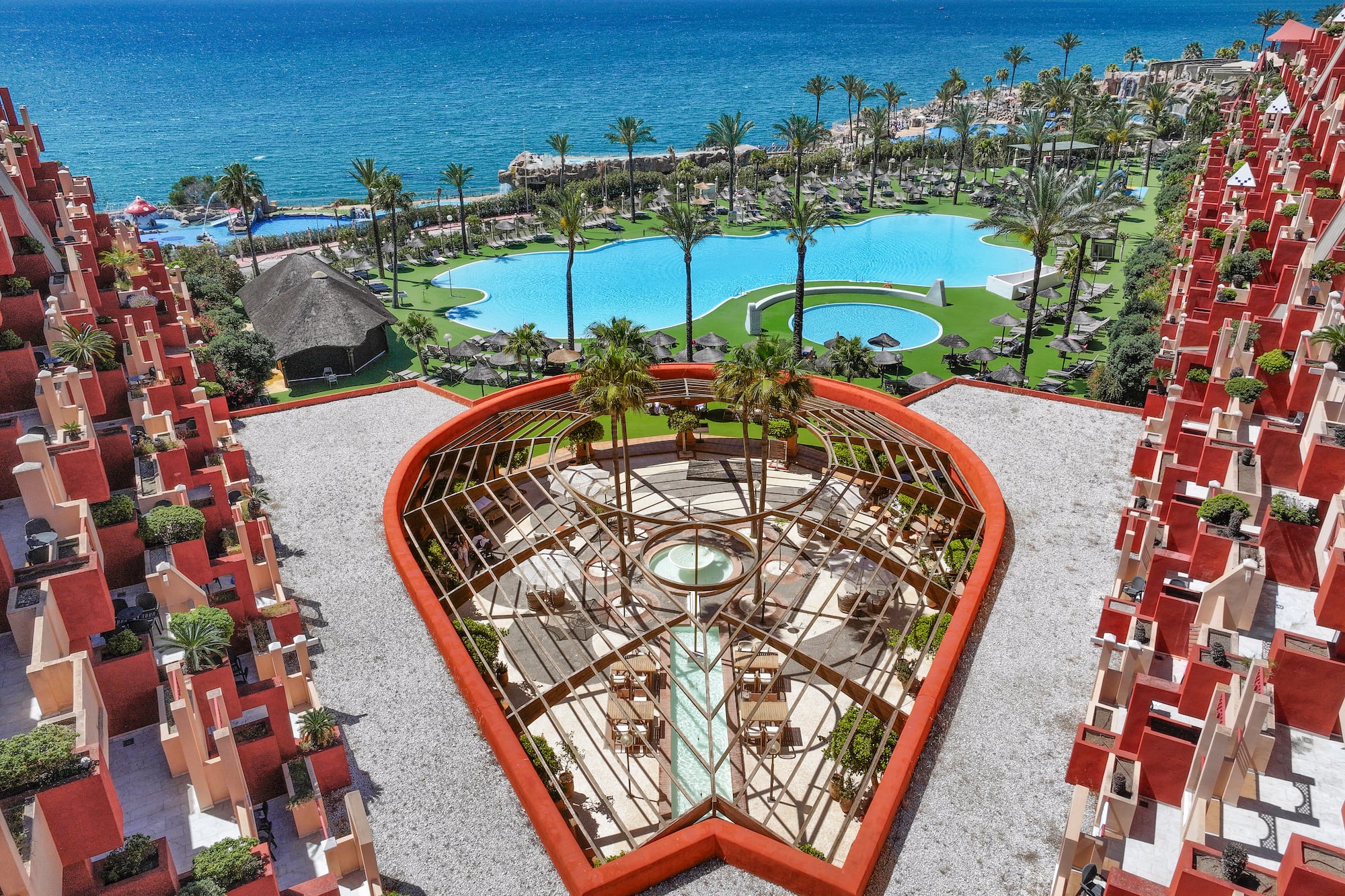a pool and buildings with palm trees and a body of water
