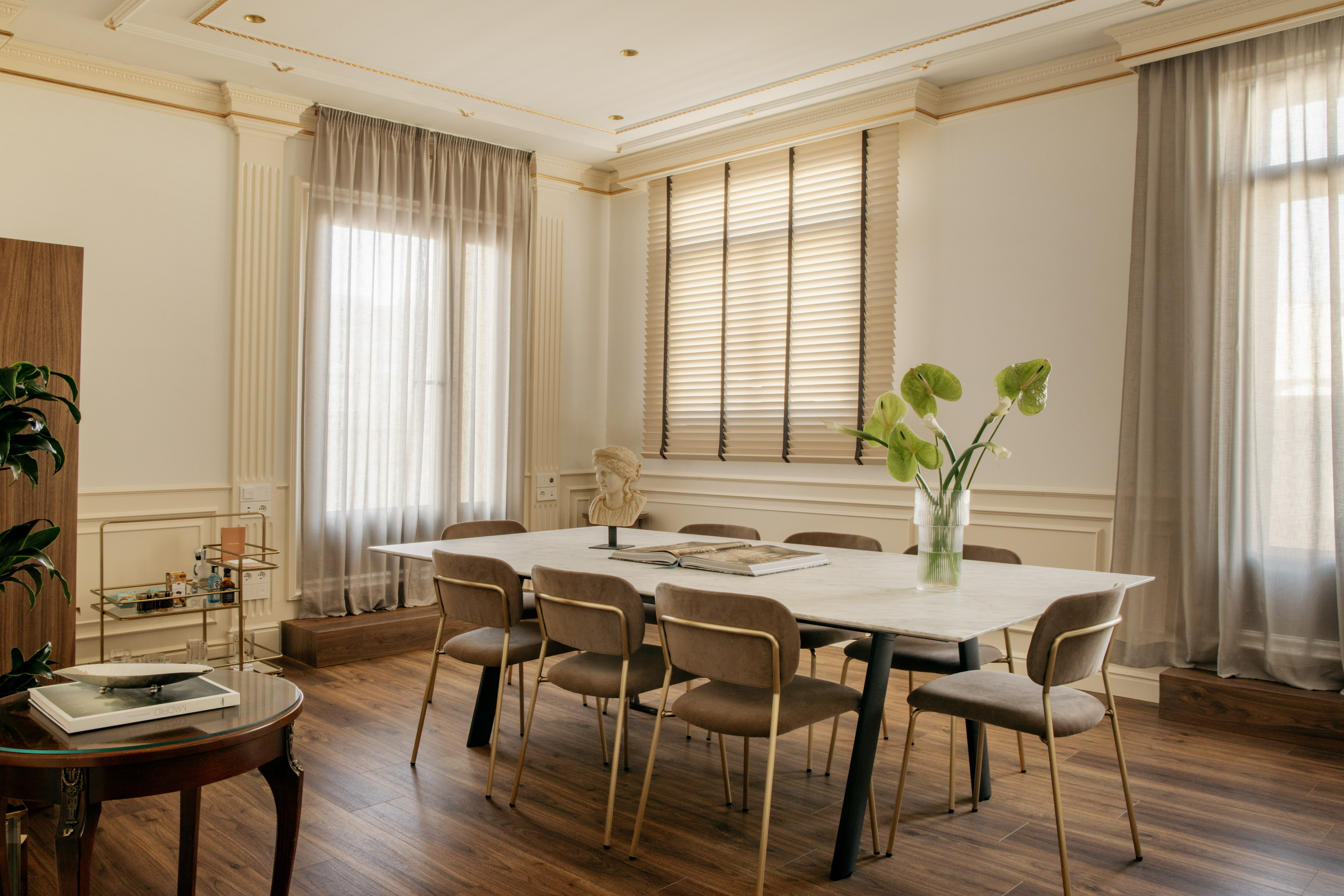 Elegant modern classic dining room with marble table, taupe chairs, and gold accents.