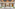 Grand modern building entrance, wood slat ceiling, marble, glass doors, landscaping.