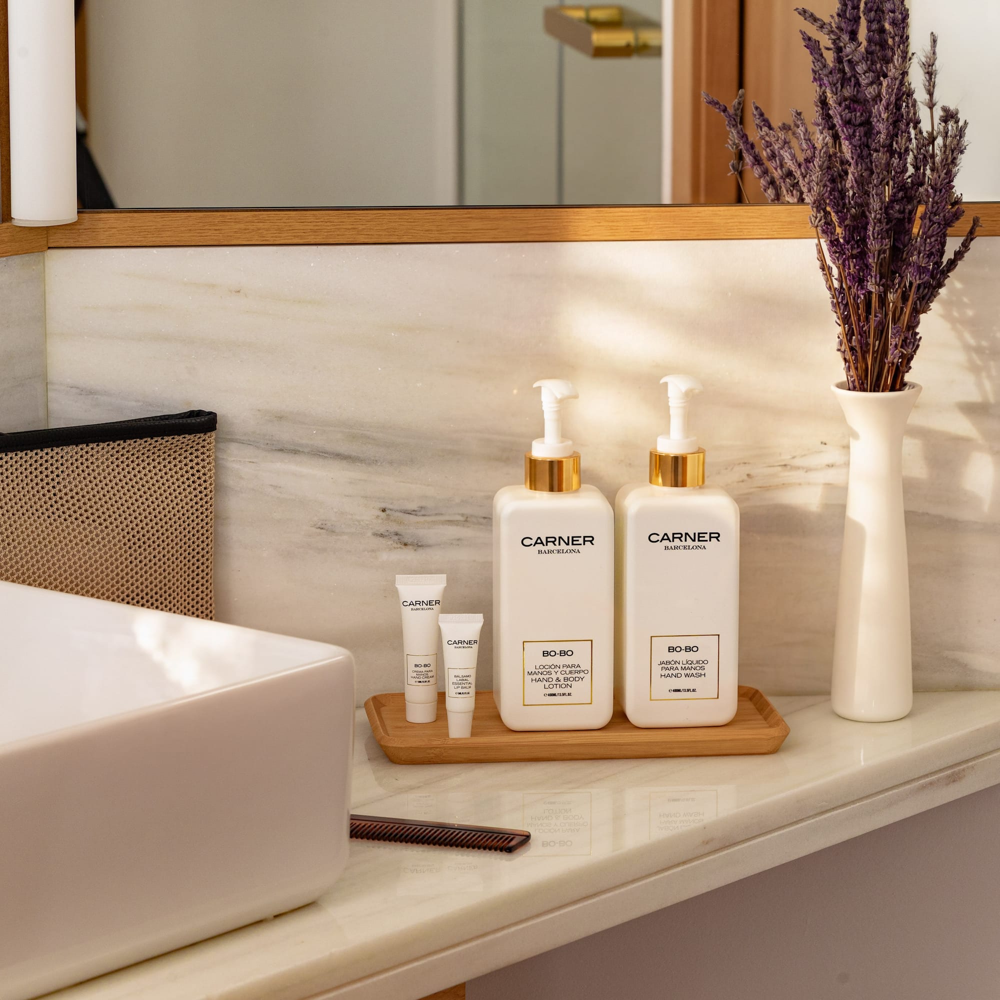 Carner Barcelona hand wash and lotion on marble bathroom counter with lavender and sink.