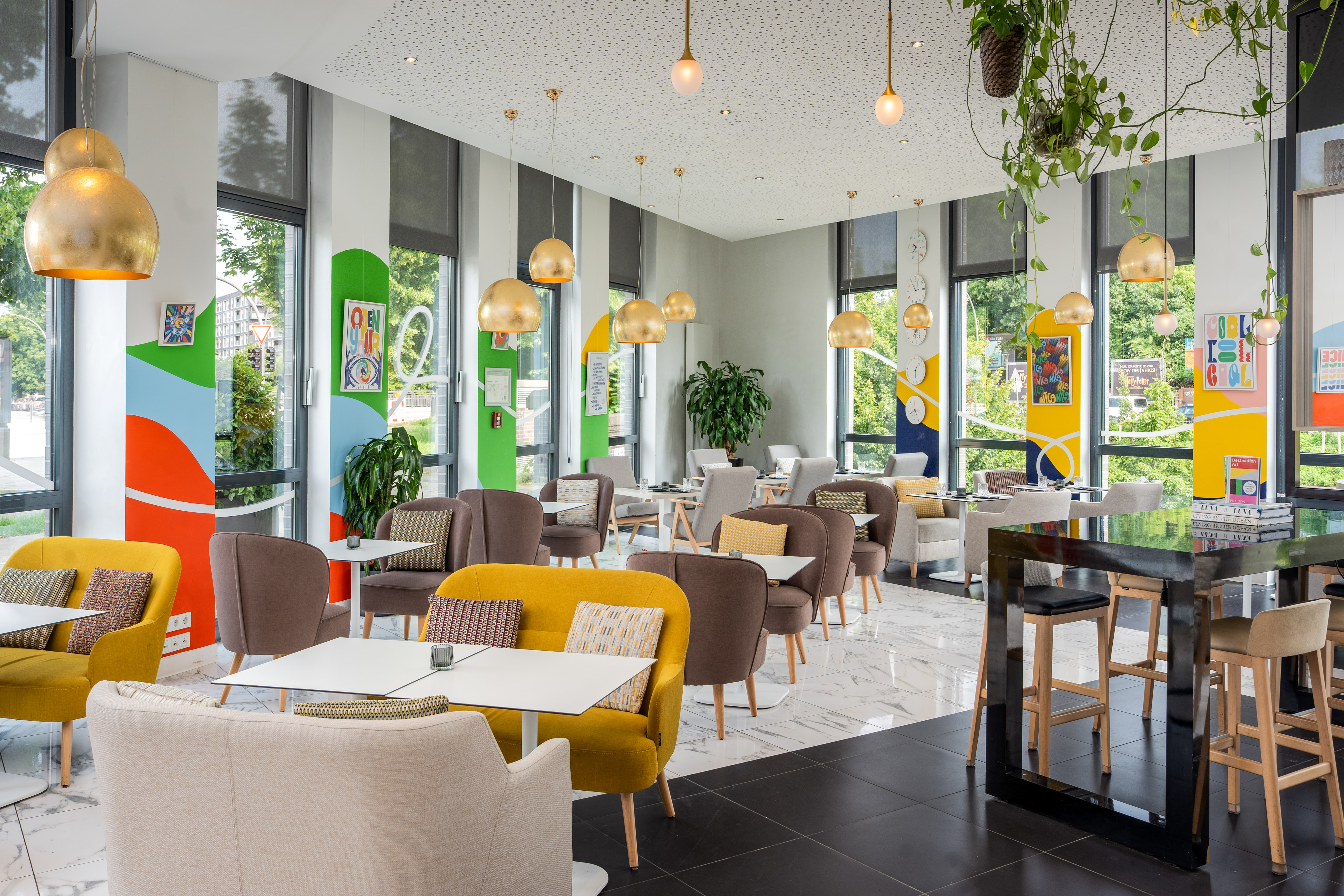 Modern colorful cafe lounge with comfortable seating, gold lights, large windows.