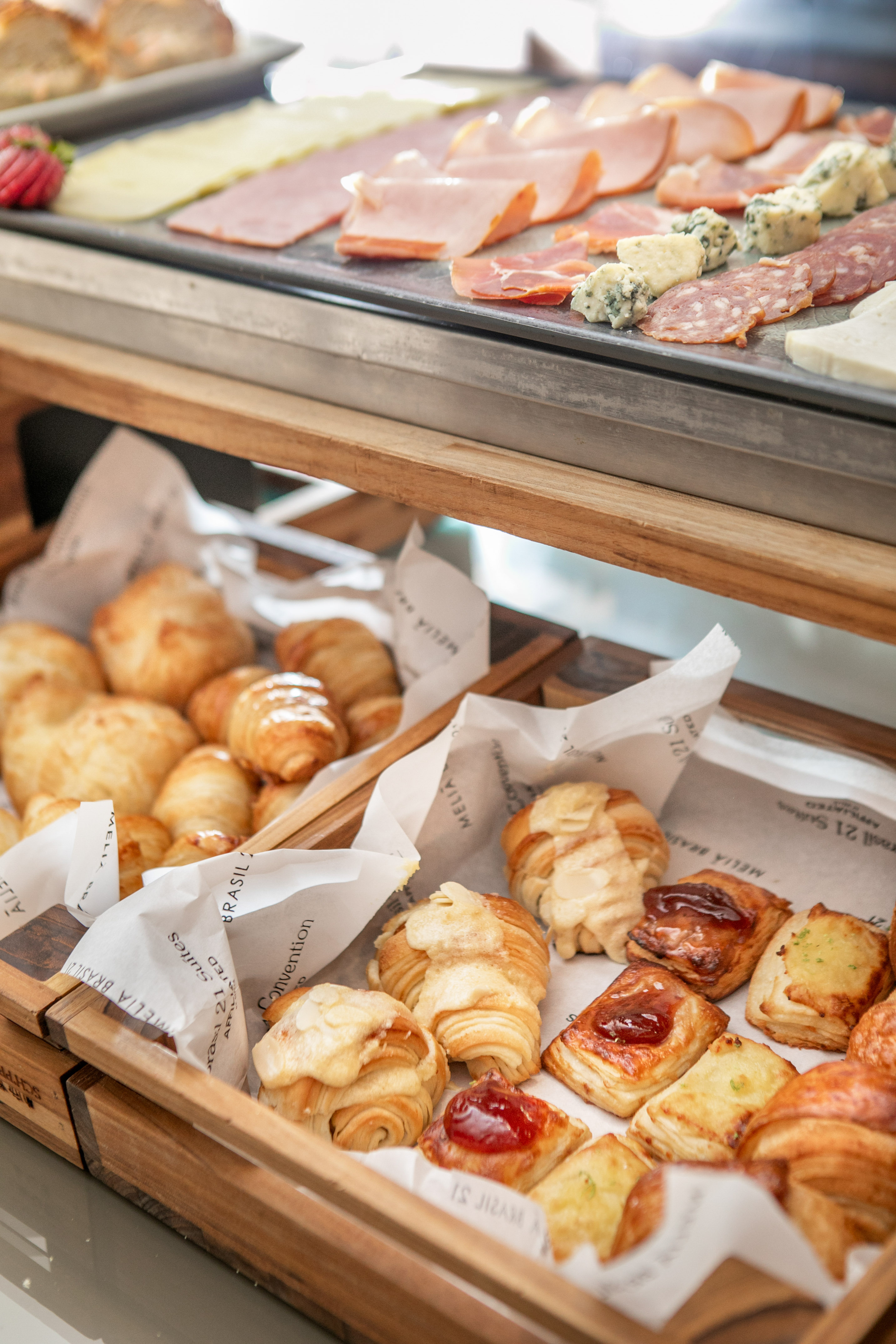 Hotel breakfast buffet with savory cold cuts, cheeses, and sweet pastries.