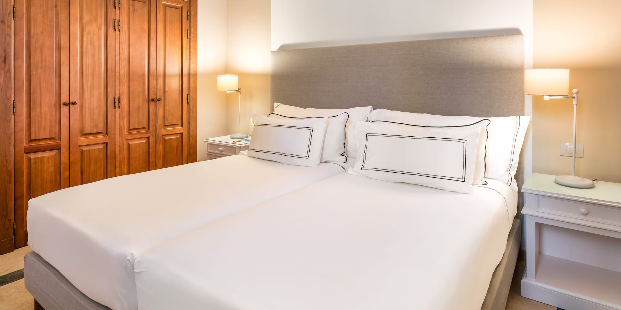 a bed with white sheets and a lamp in a room