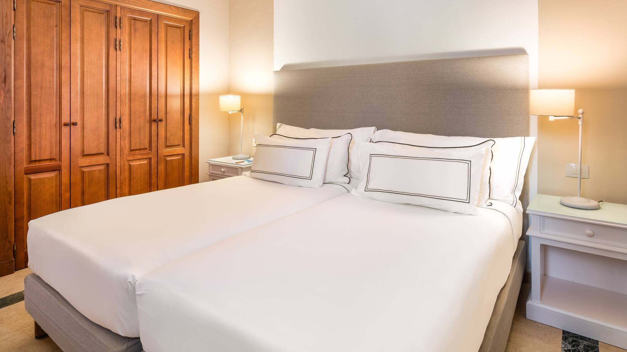 a bed with white sheets and a lamp in a room