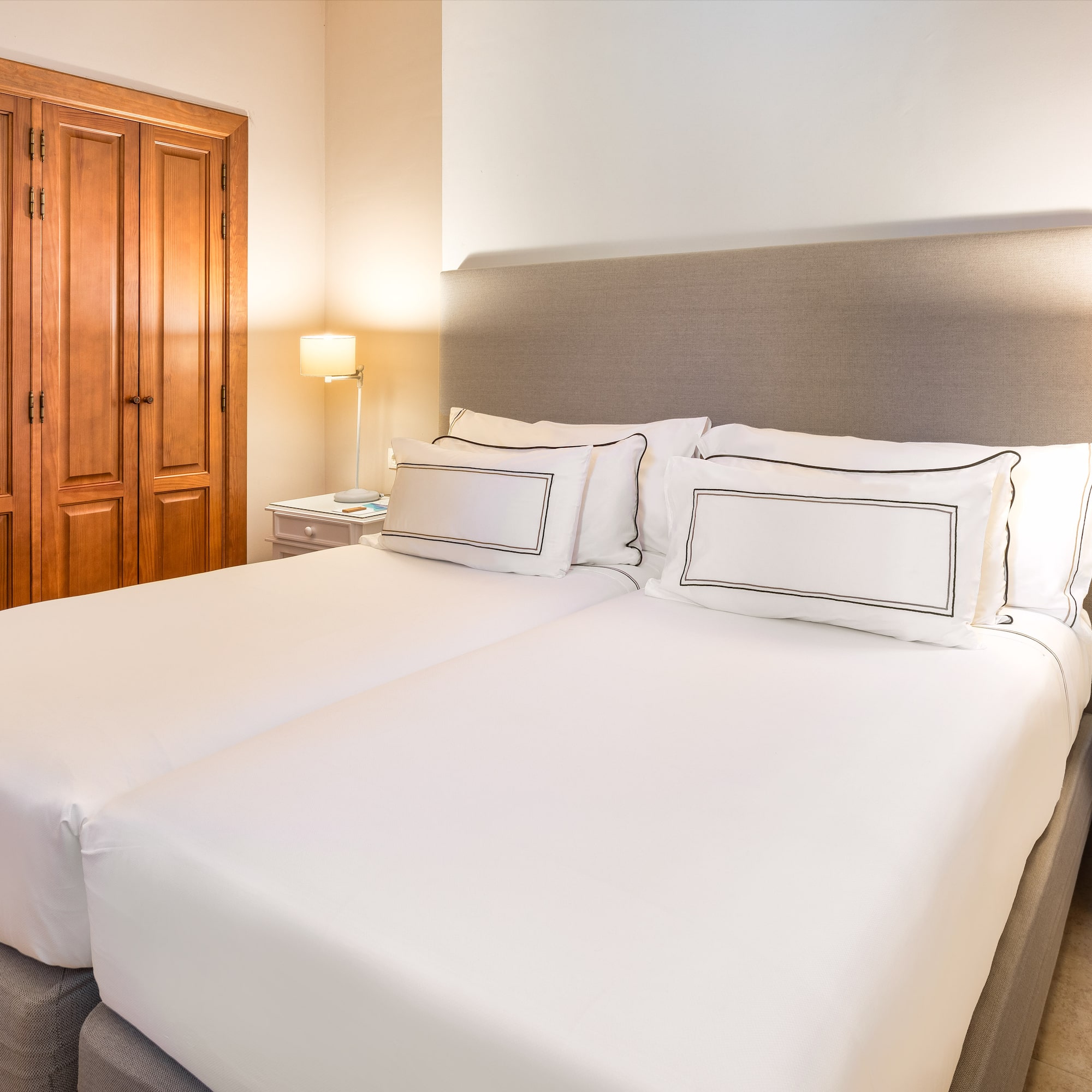 a bed with white sheets and a lamp in a room