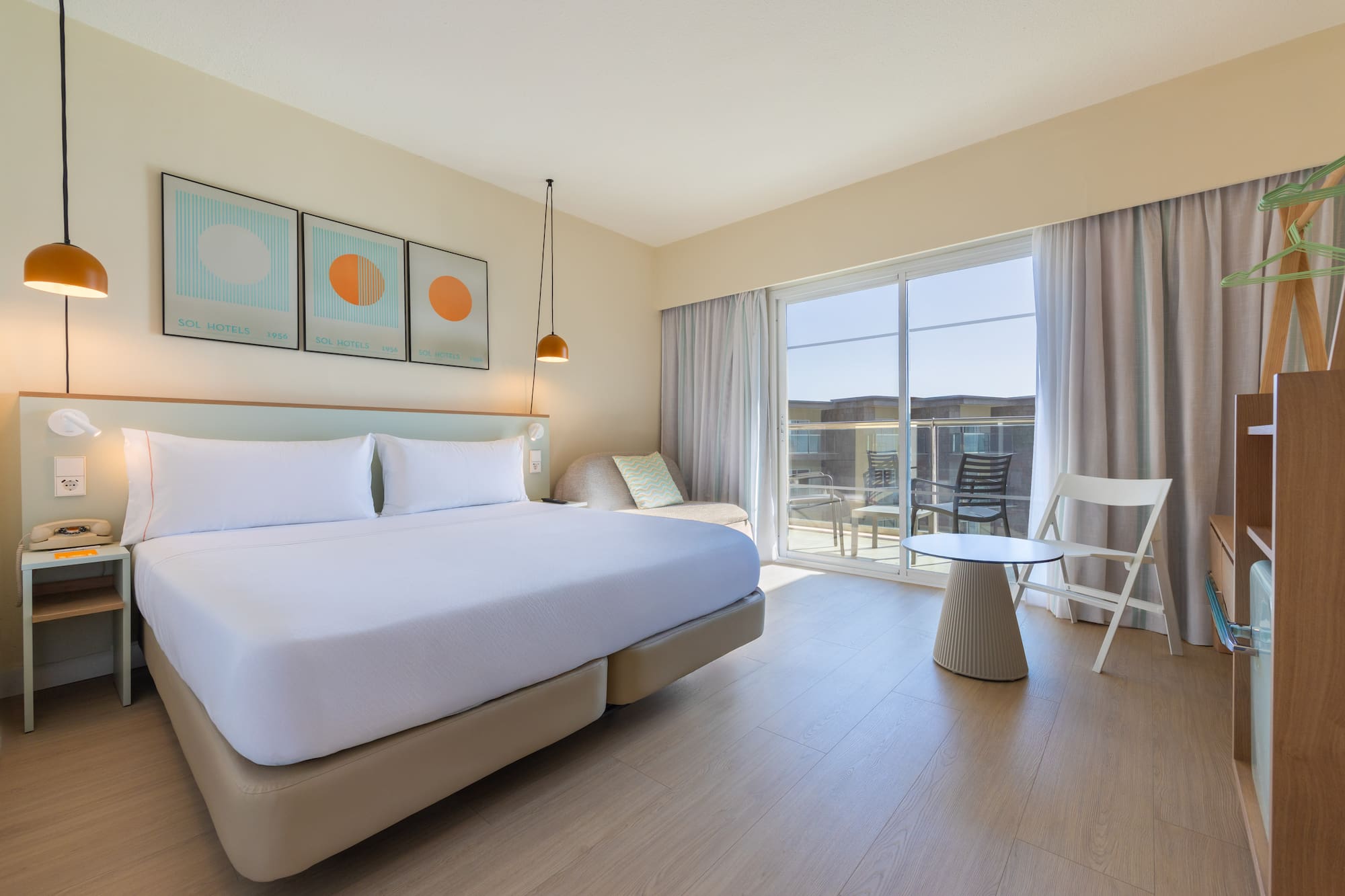 Bright Sol Hotels bedroom with king bed, balcony access, and light decor.