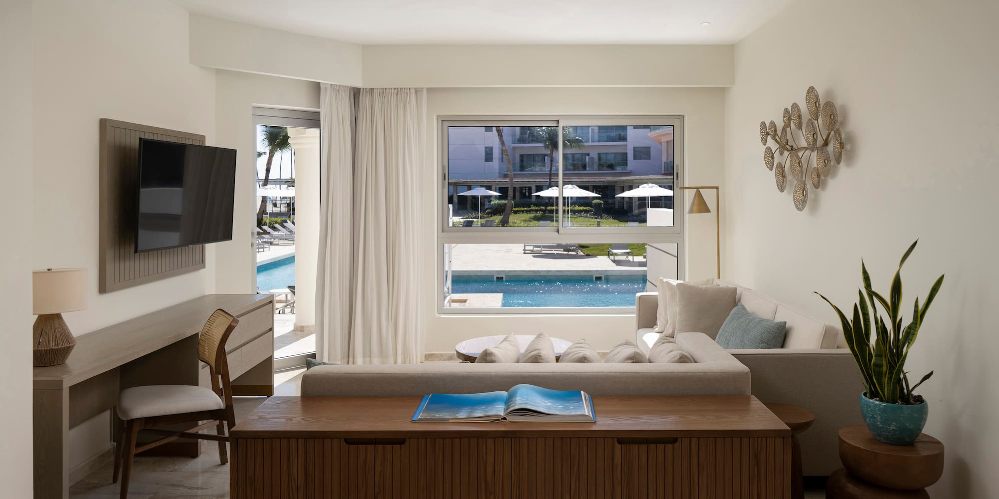 a living room with a television and a pool in the background