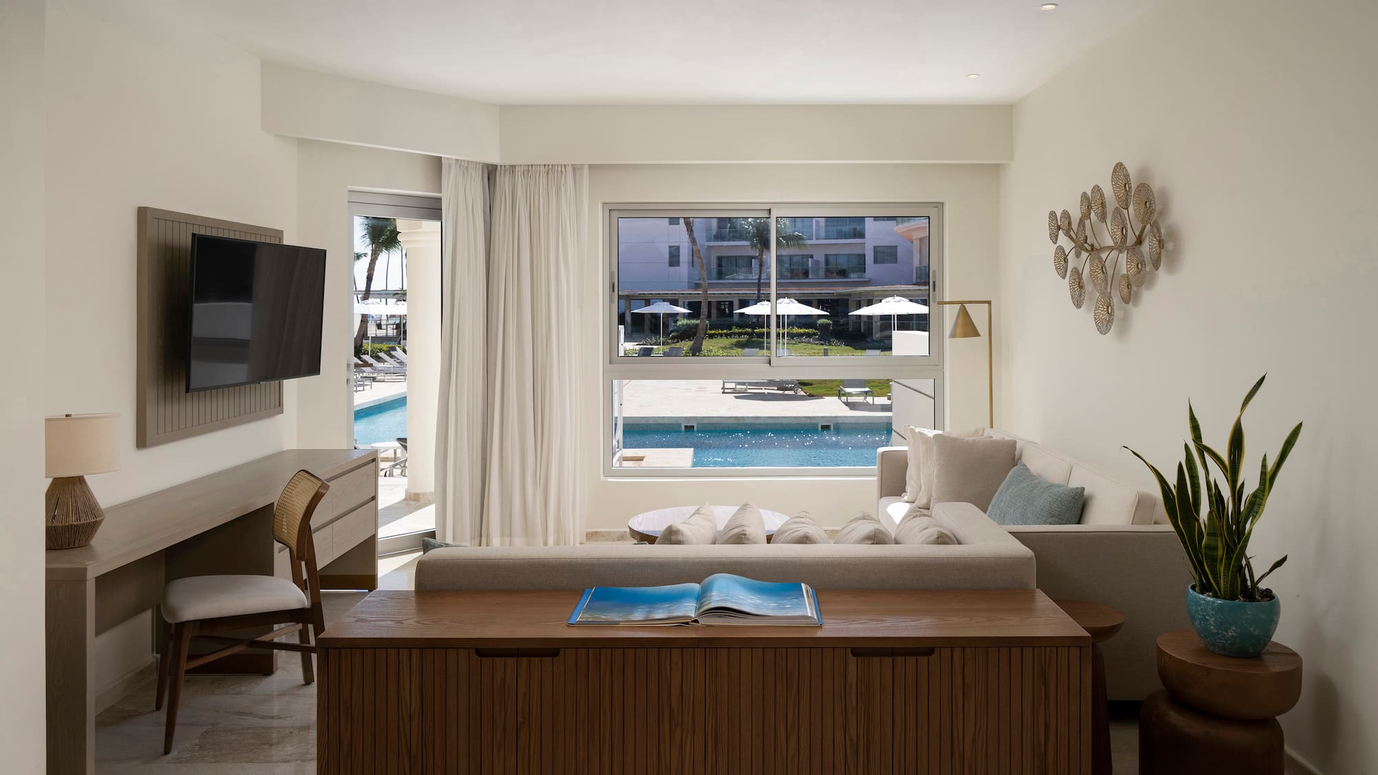 a living room with a television and a pool in the background