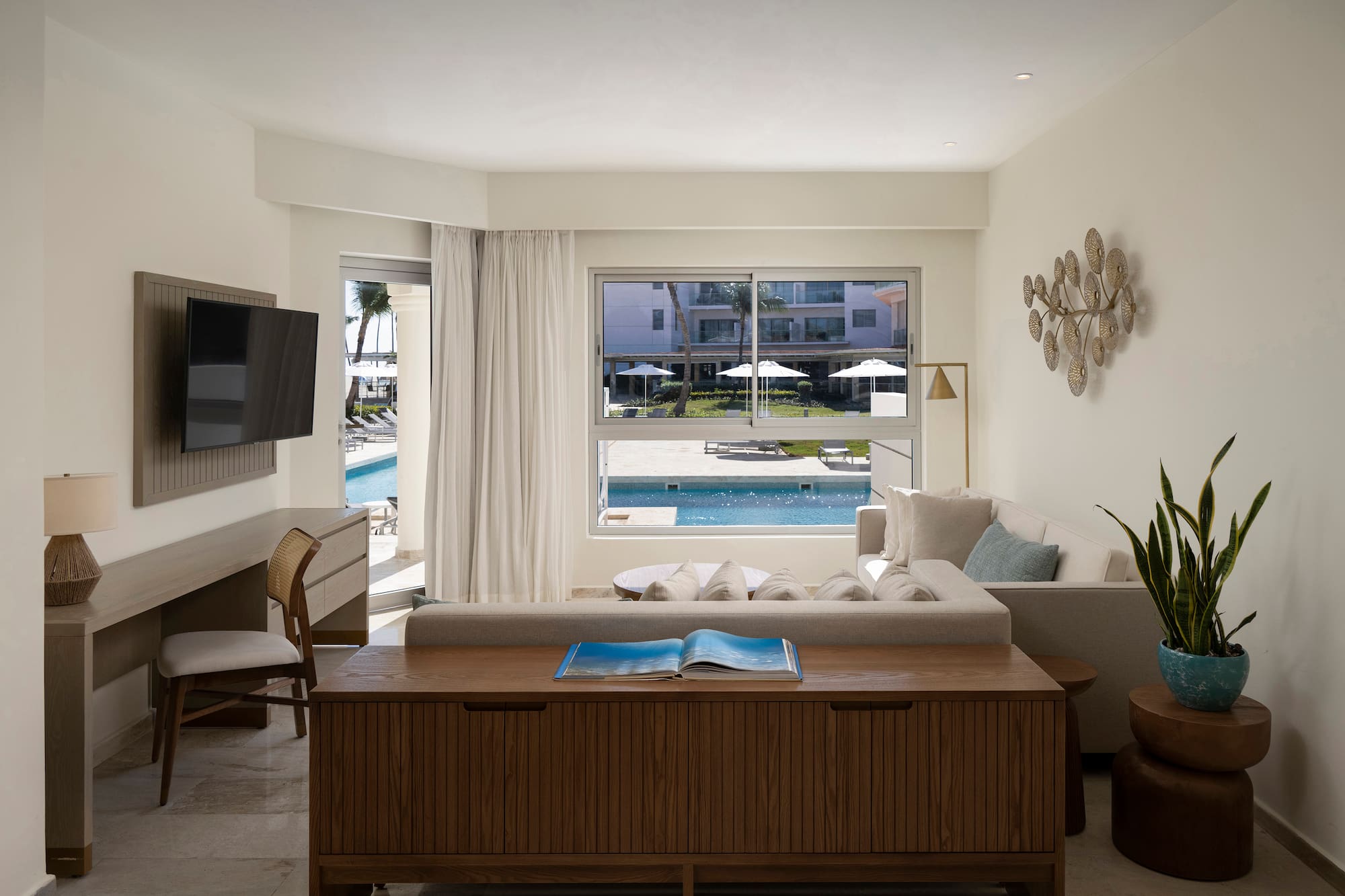 a living room with a television and a pool in the background