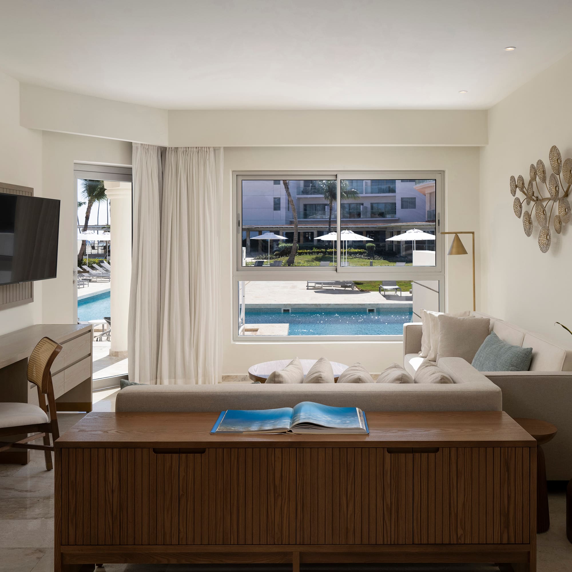 a living room with a television and a pool in the background