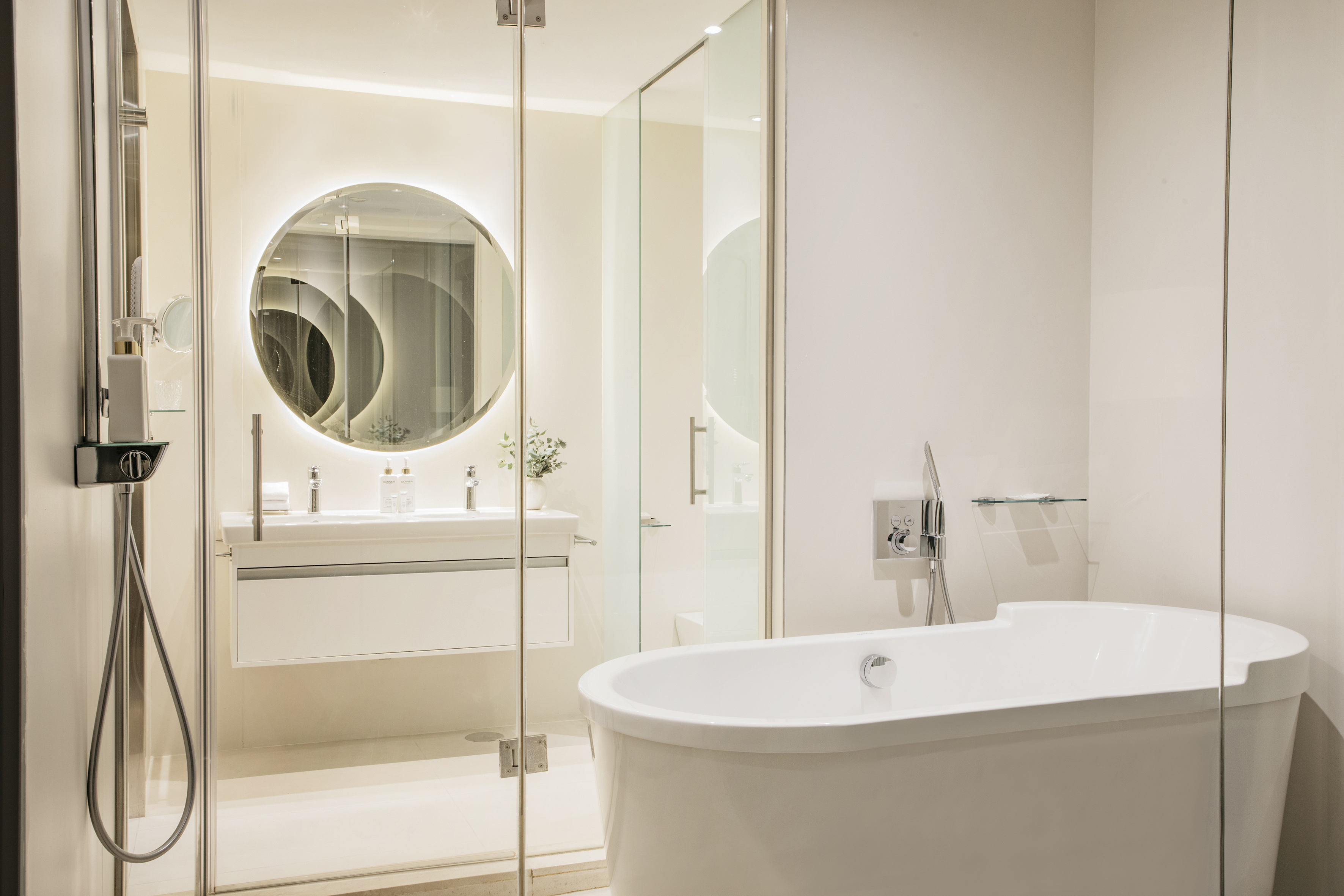 Clean modern bathroom with freestanding tub, glass shower, and backlit mirror.