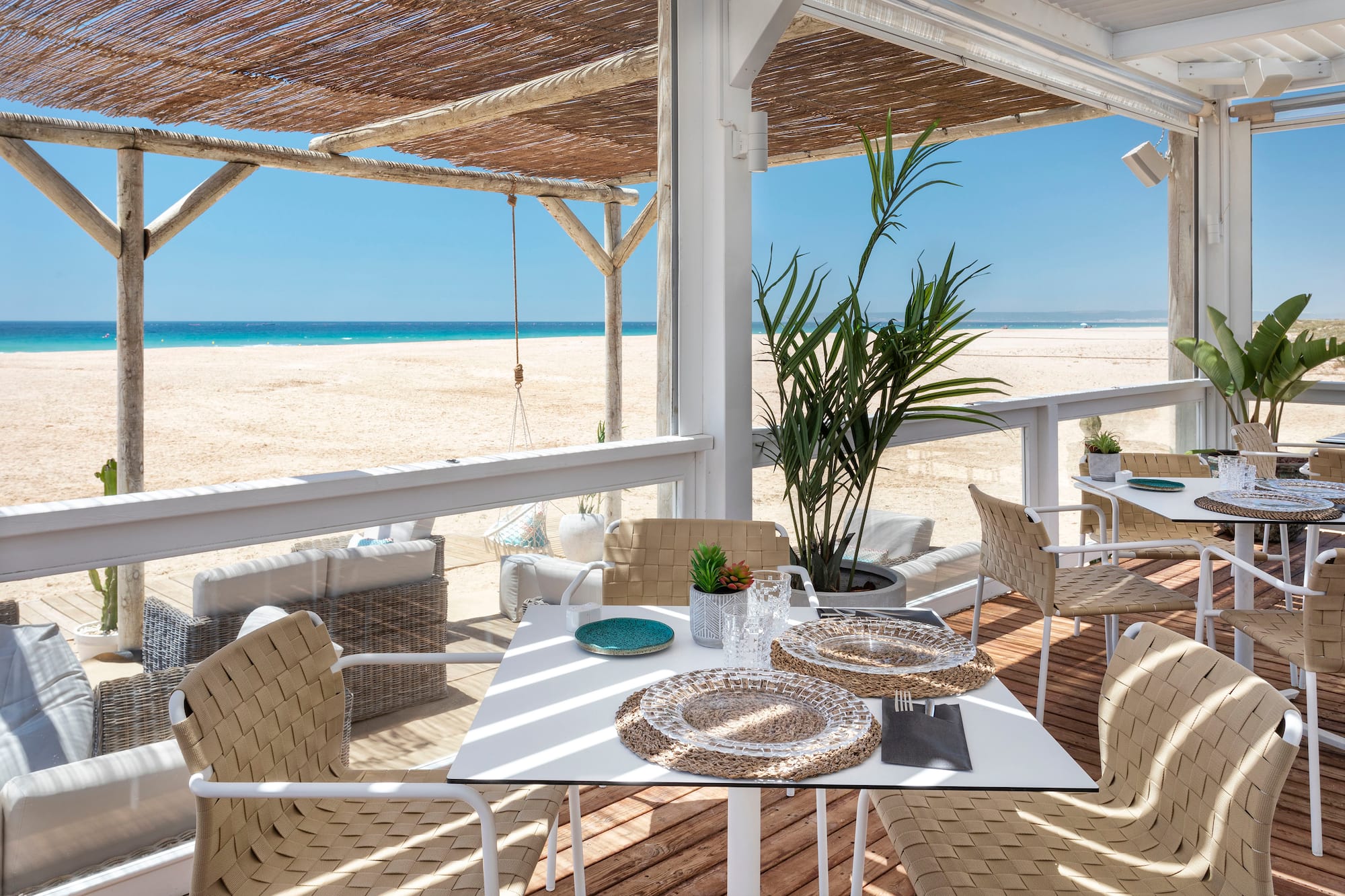 a table and chairs on a deck with a beach view