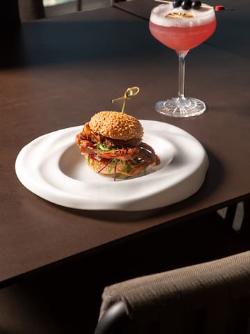 a burger on a plate next to a glass of wine