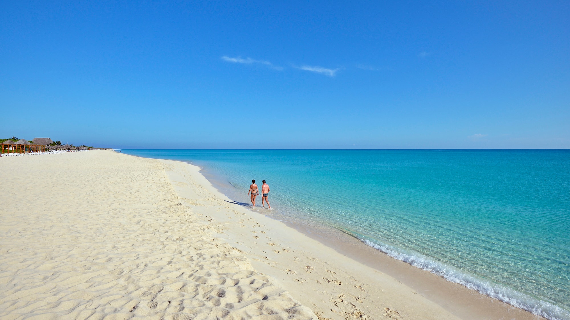 two people walking on a beach