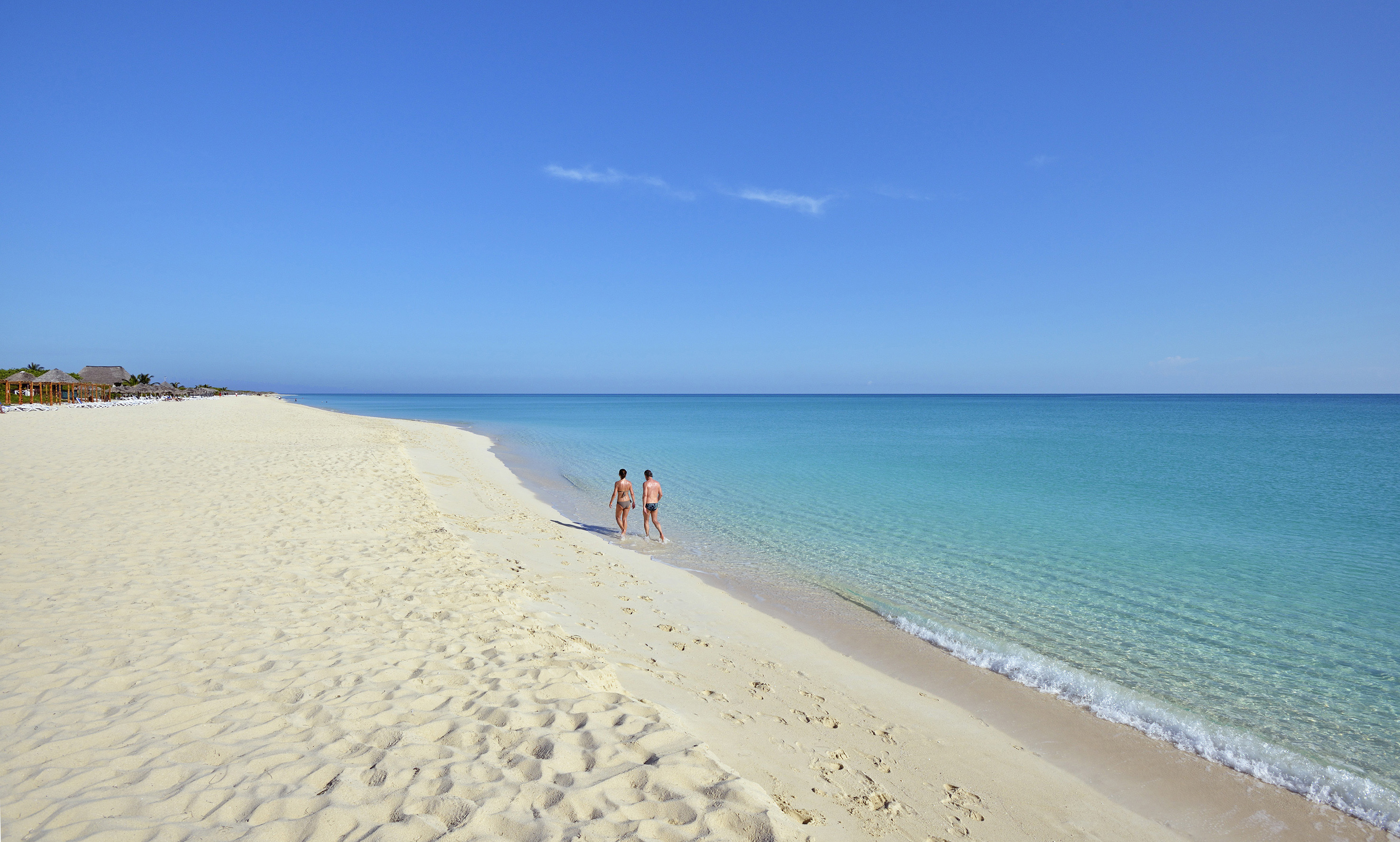 two people walking on a beach