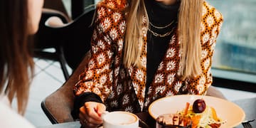 a woman sitting at a table with a cup of coffee and food