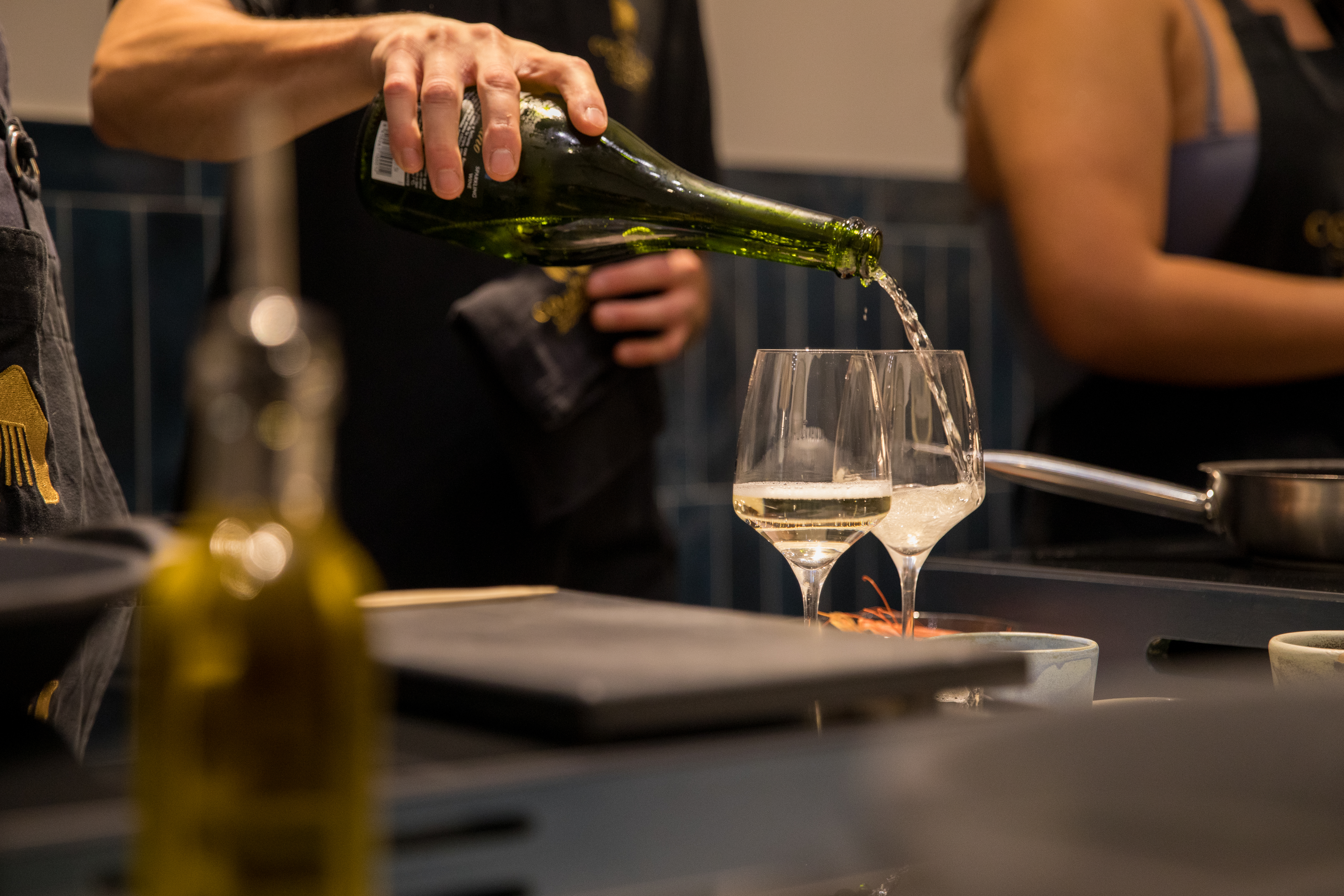 a person pouring wine into glasses