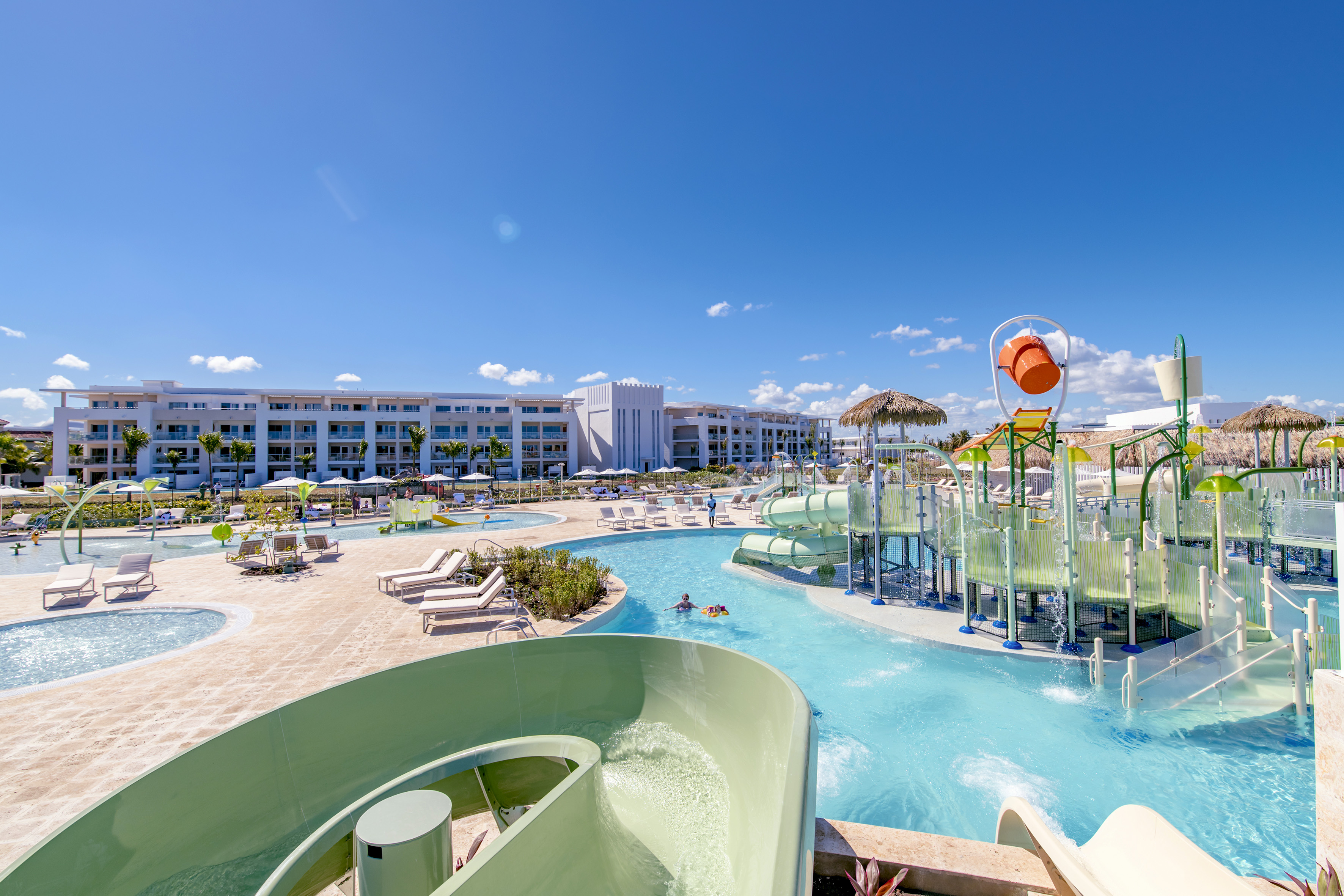 Vibrant resort water park with splash pad, slides, pools, and hotel.