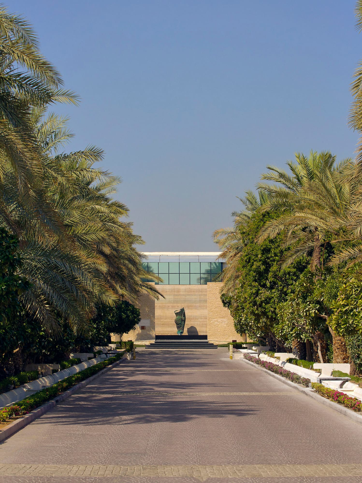 a road with palm trees and a statue on the side
