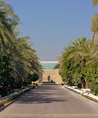 a road with palm trees and a statue on the side