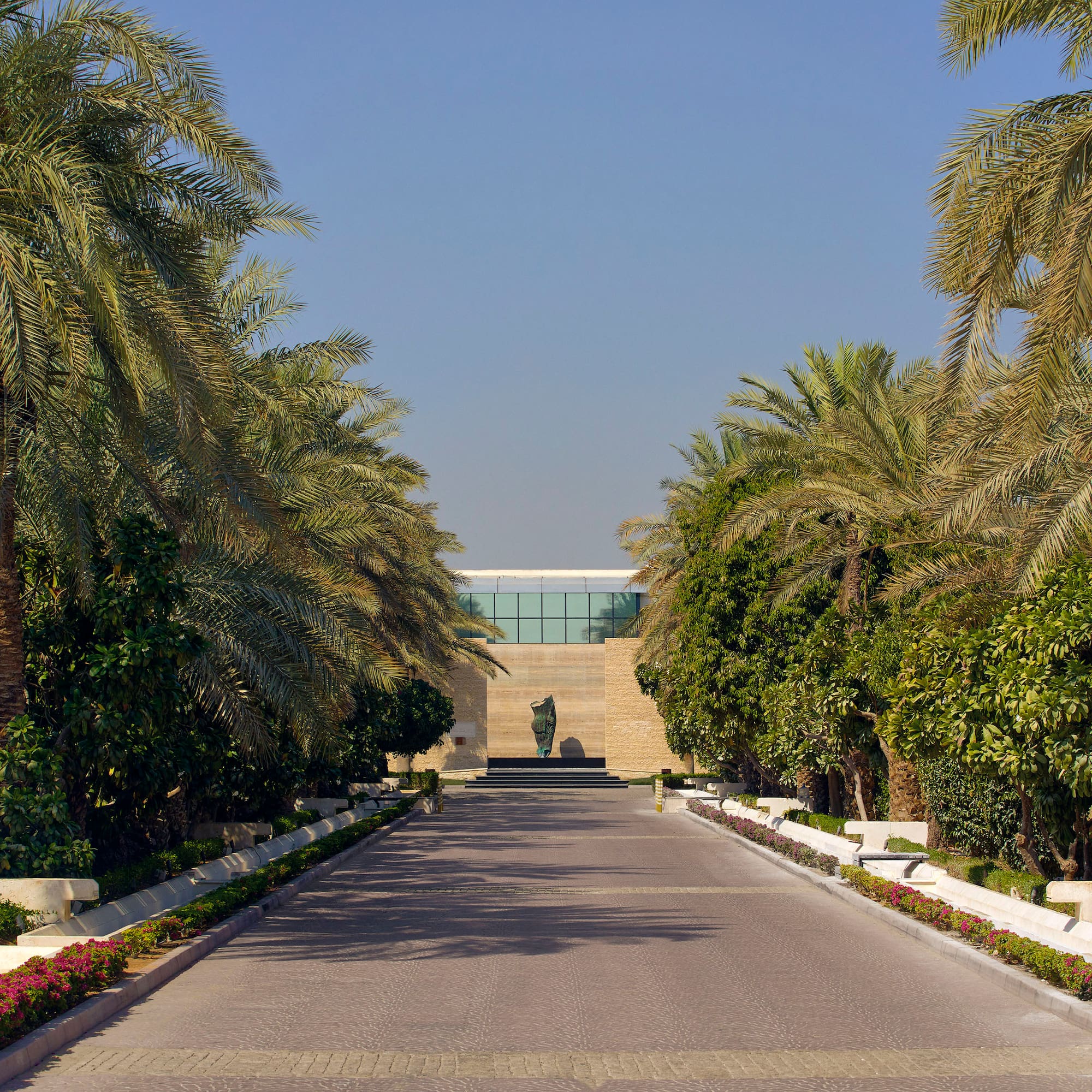 a road with palm trees and a statue on the side