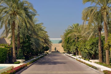 a road with palm trees and a statue on the side