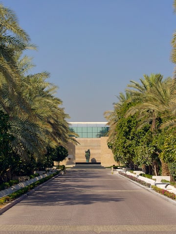 a road with palm trees and a statue on the side
