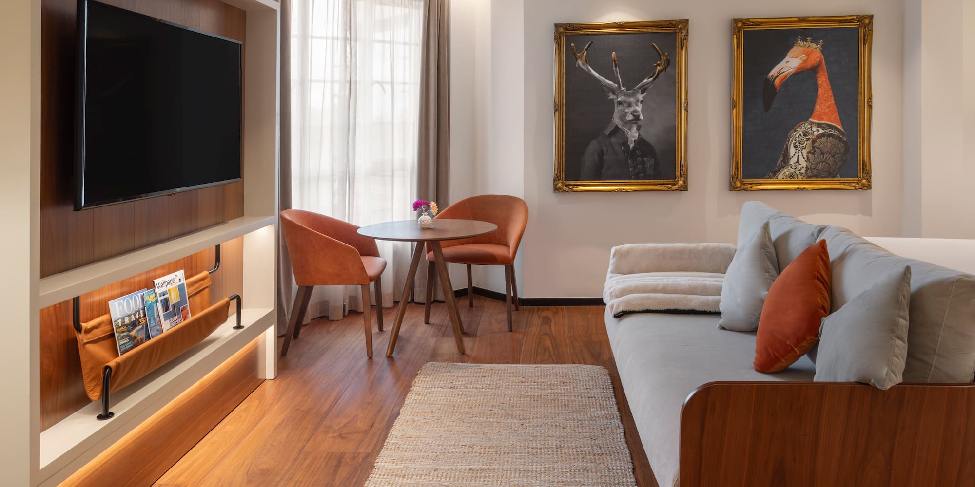 Hotel suite living space with TV, sofa, dining area, and framed animal art.