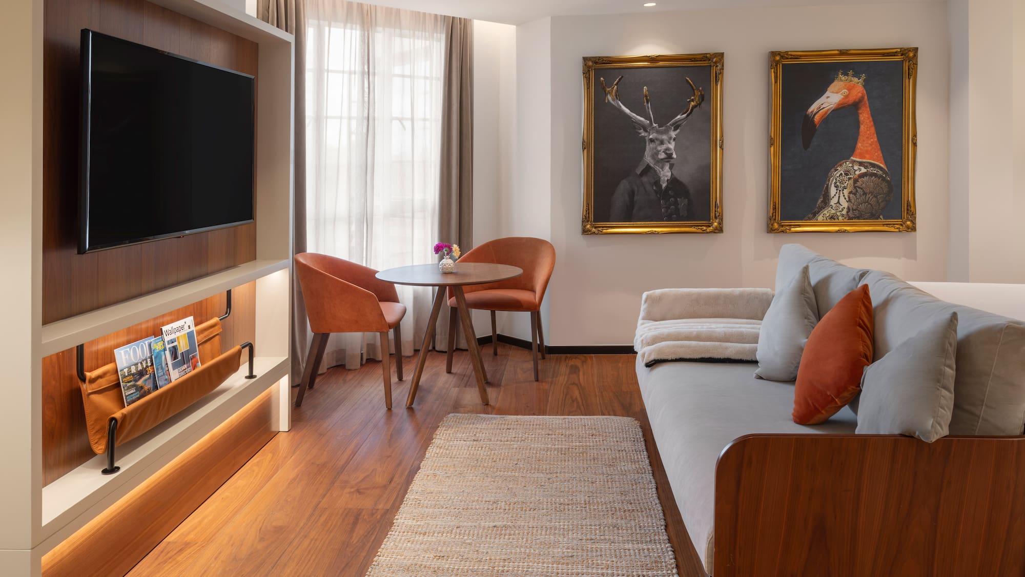 Hotel suite living space with TV, sofa, dining area, and framed animal art.