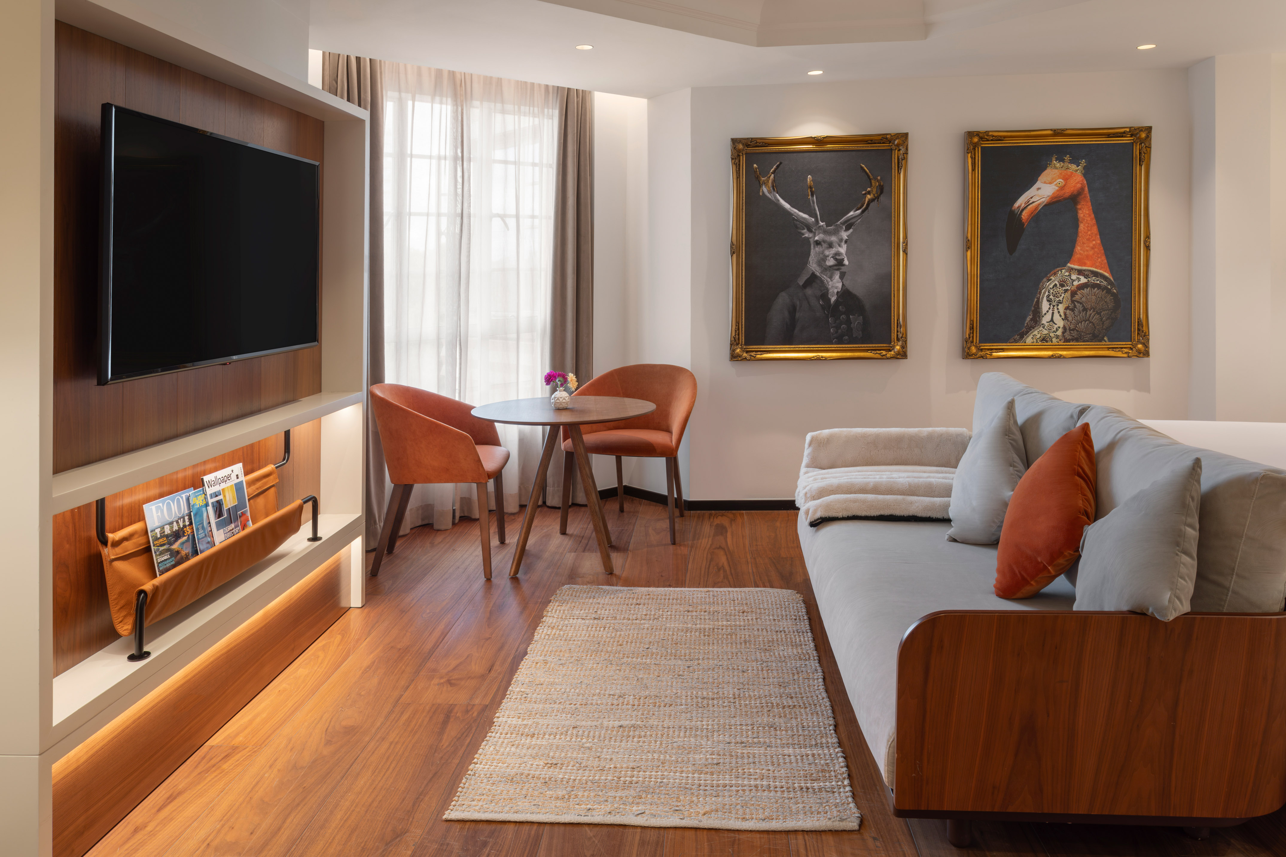 Hotel suite living space with TV, sofa, dining area, and framed animal art.