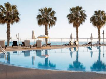 a pool with palm trees and chairs